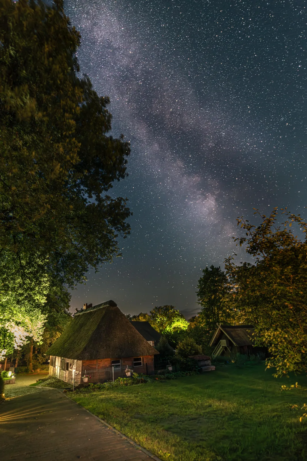 Sternenhimmel und Milchstraße über dem ruhigen Heidehof bei Nacht
