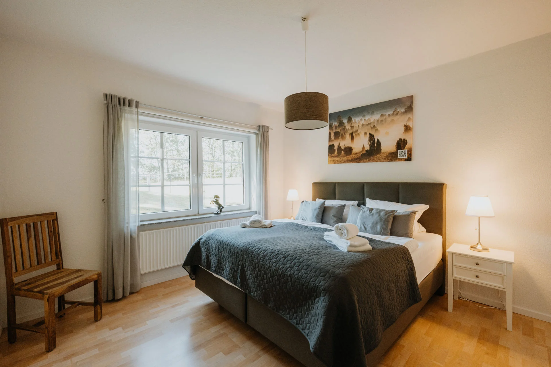 Haverbecker Heide: Schlafzimmer mit Doppelbett, Holzstuhl und großem Fenster