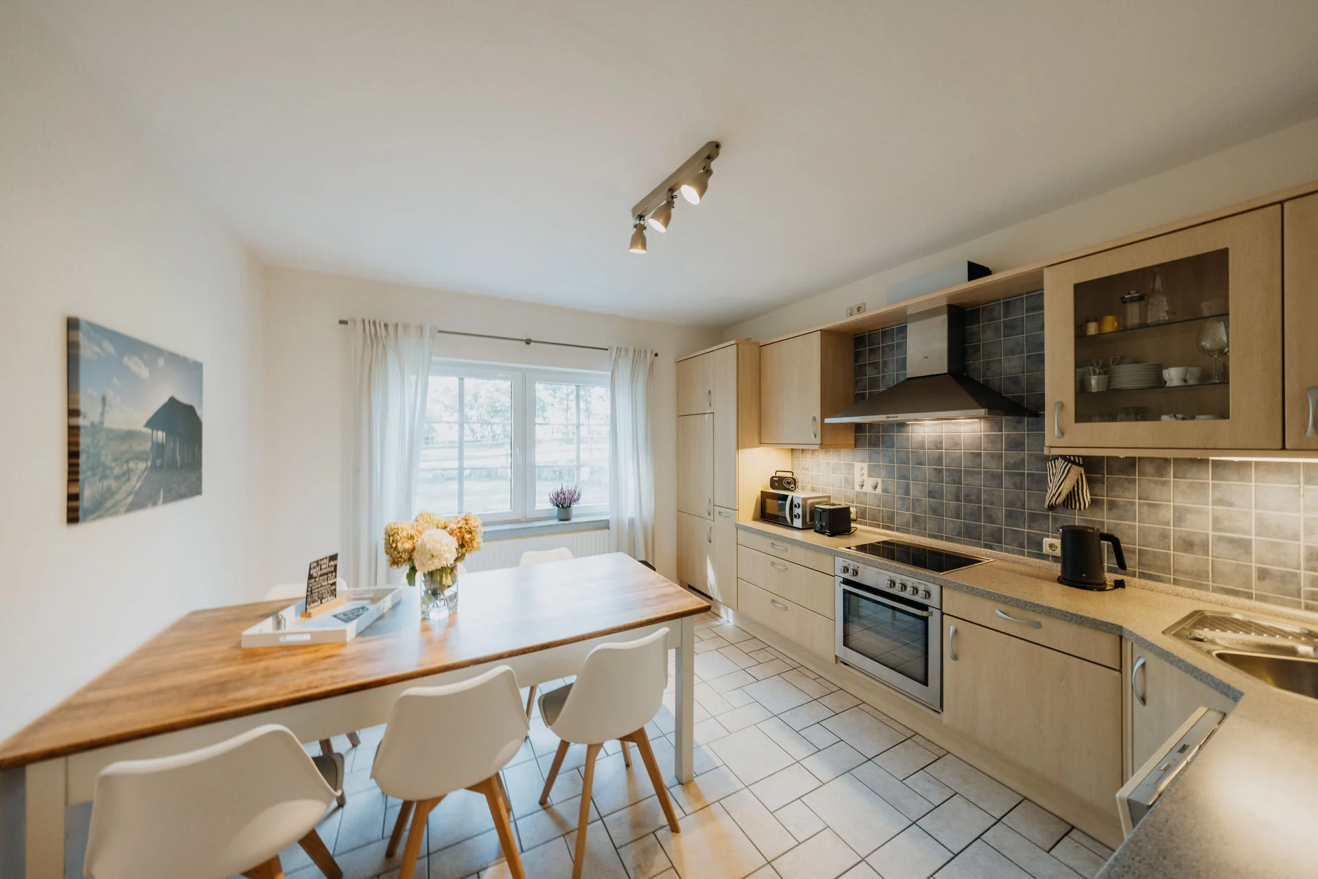 Haverbecker Heide: Küche und Esstisch mit weißen Stühlen und Blumenschmuck