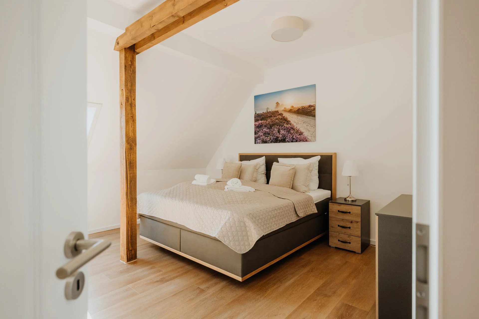 Schlafzimmer mit Doppelbett, Holzschrank und sichtbarem Holzbalken in der Ferienwohnung HeidePanorama