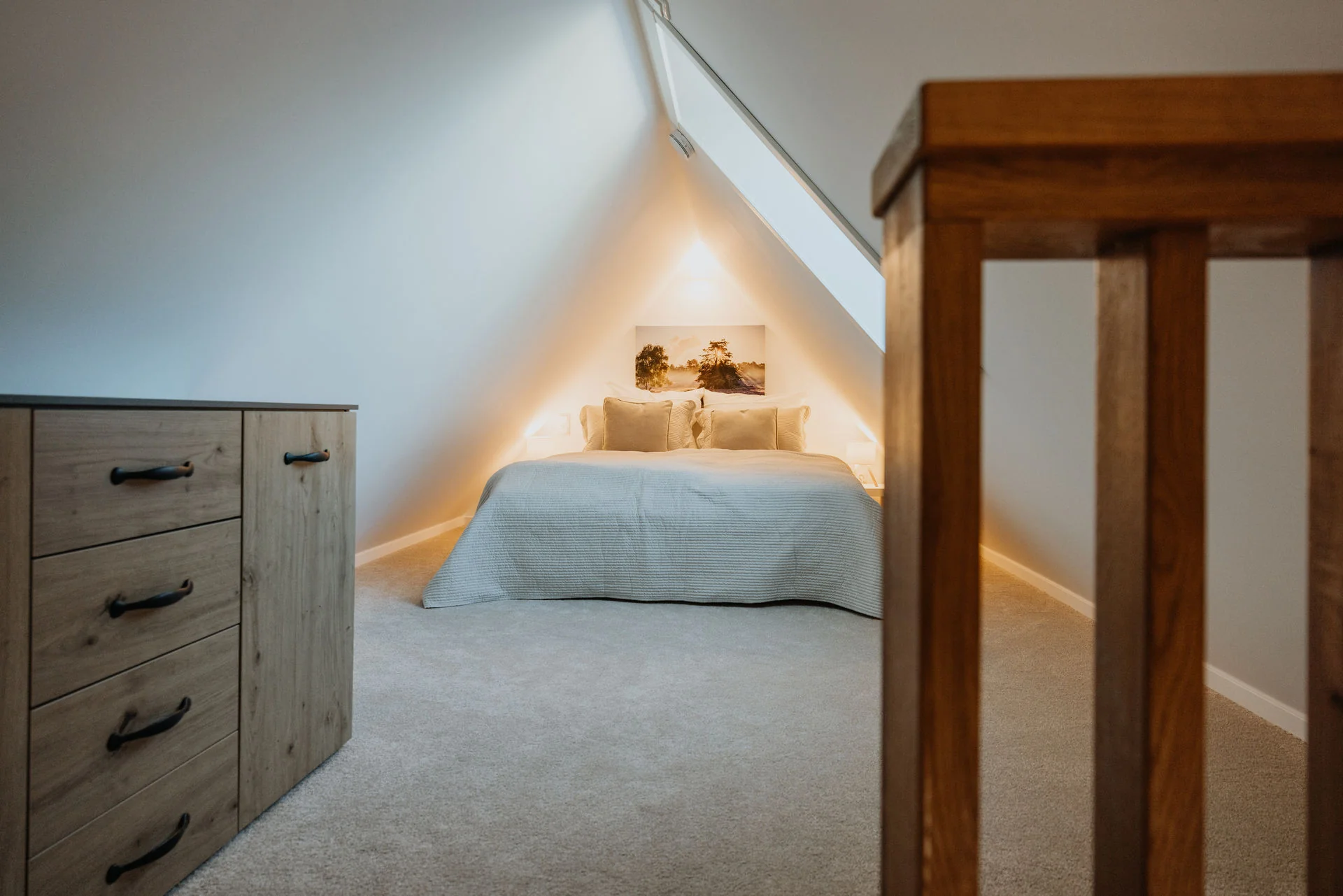 HeidePanorama: Schlafzimmer unter der Dachschräge mit Dachfenster und Holzkommode