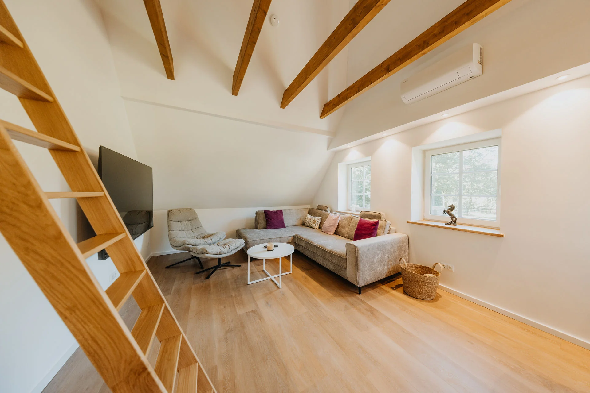Koppelidyll: Sofaecke mit Sessel, Couchtisch und Fenstern unter sichtbaren Dachbalken